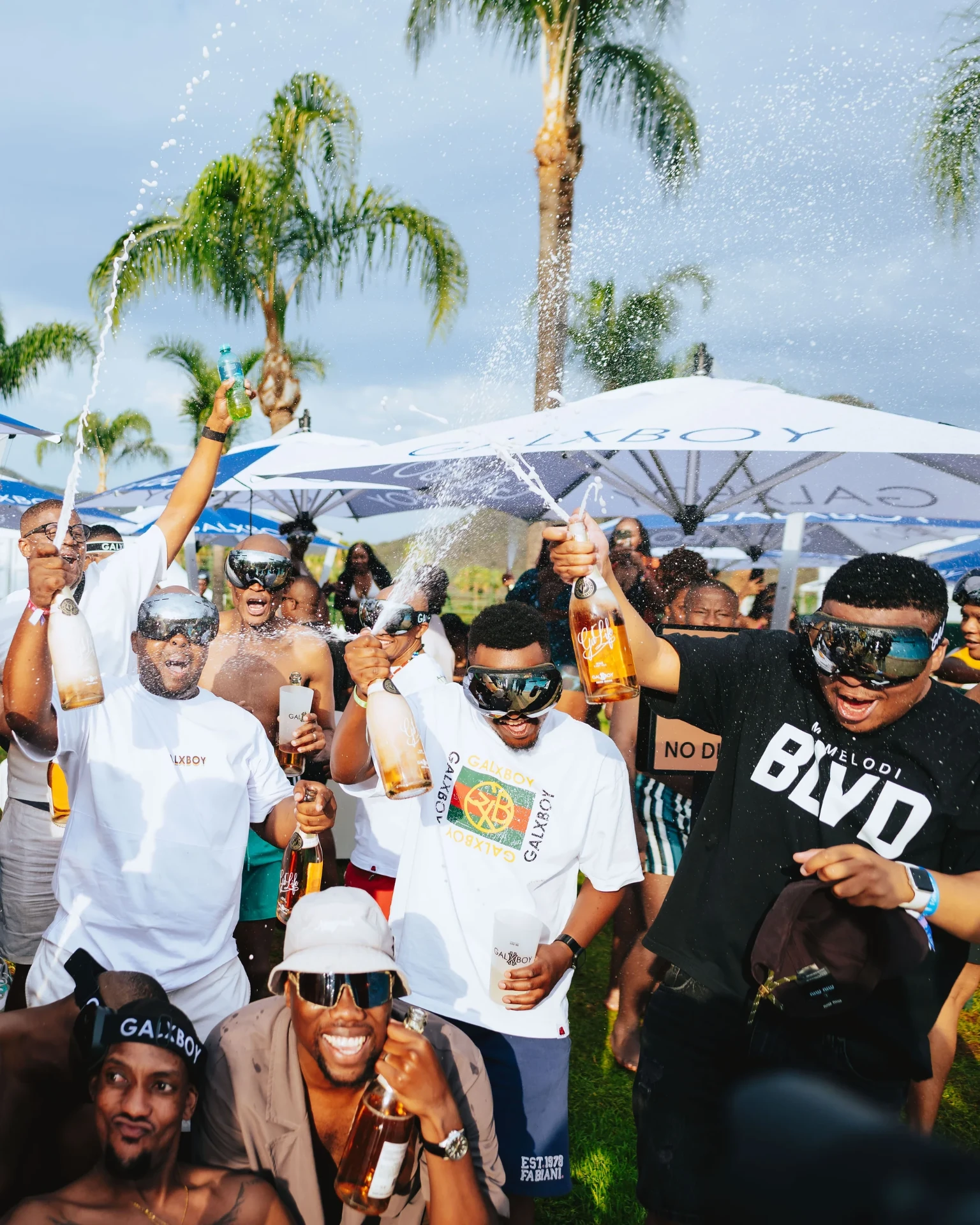 Crowd spraying bottles under branded umbrellas at the takeover